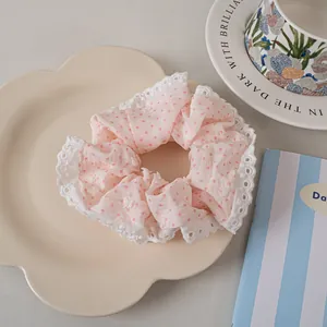 Detailed view of pink polka dot scrunchie with lace edges on a floral decorative tray