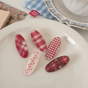Detail of five-piece red plaid hair clip set on a ceramic plate with vintage patterns