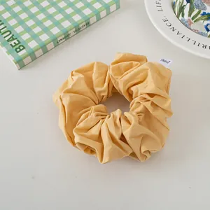 Detail of a ginger yellow pleated cotton scrunchie with brand label on a cozy background