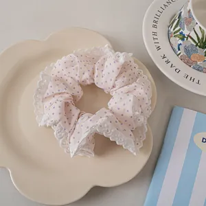 Close-up of pink polka dot scrunchie with white lace trim on a floral tray