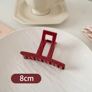 Makroaufnahme der 8cm tiefroten quadratischen Haarklammer auf weißem Dekoteller