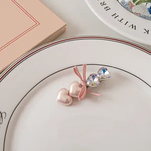Dettaglio di fermaglio con cuori di perle rosa e fiocco scintillante su vassoio