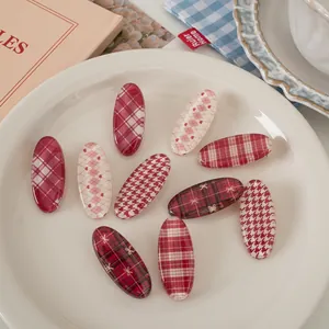 Detail of vintage red plaid and houndstooth oval hair clips on a ceramic plate