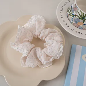 Close-up of pink polka dot hair scrunchie with delicate white lace edges in a ceramic dish