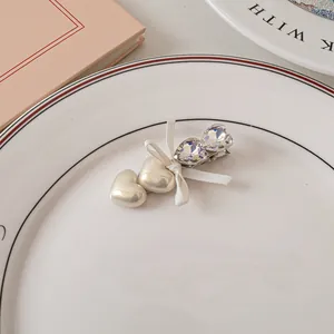 Dettaglio del fermaglio per capelli cuore perlato con strass e fiocco bianco nel piatto