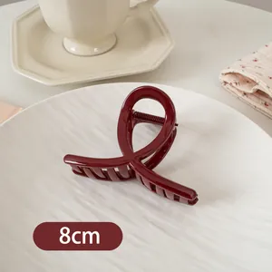 Detailaufnahme der glänzenden burgunderroten 8cm Haarklammer auf einem weißen Keramiktablett
