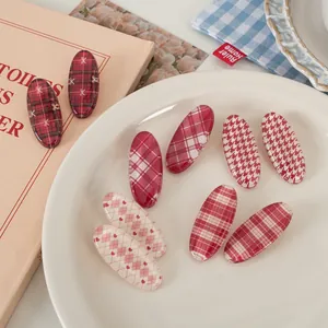 Vintage red plaid oval hair clips set with houndstooth and heart patterns in a ceramic plate