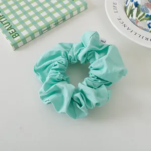 Detailed close-up of mint green fabric scrunchie with a woven brand label