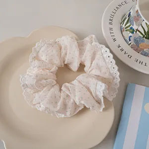 Detail of lace-trimmed polka dot scrunchie on a decorative ceramic plate with a coffee cup