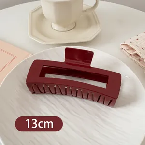 Detailaufnahme einer 13 cm dunkelroten rechteckigen Haarklammer auf einem weißen Teller