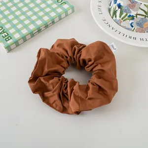 Detail of a large dark brown scrunchie with a stylish white woven logo tag on fabric