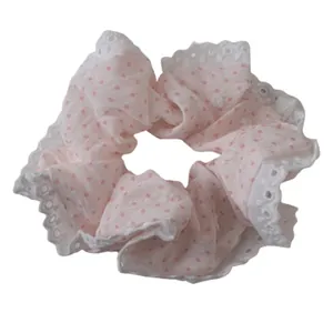 Pink polka dot hair scrunchie with white lace edges and soft fabric texture on white background