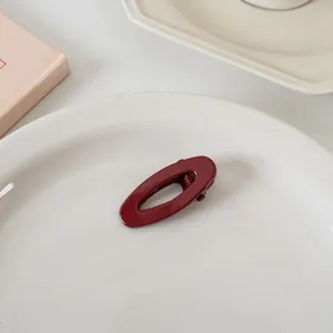 Vue détaillée d'une pince à cheveux ovale bordeaux sur une assiette en céramique
