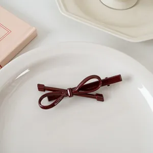 Détail d'une barrette à cheveux nœud bordeaux avec finition brillante sur plat blanc