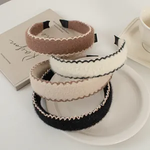 Détail de serre-têtes en laine aux tons café avec broderie élégante sur table blanche