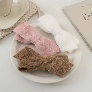 Drei Woll-Haarschleifen-Clips in Rosa, Beige und Braun auf gemütlichem Hintergrund