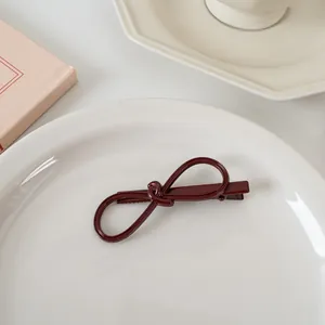 Détails d'une pince à cheveux rouge foncé en forme de nœud sur une assiette en céramique