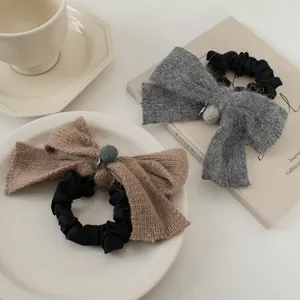 Détail de chouchous à nœuds tricotés café et gris avec breloques métalliques et texture douce