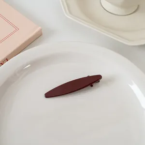 Vue détaillée d'une pince à cheveux vintage en résine bordeaux sur une assiette blanche