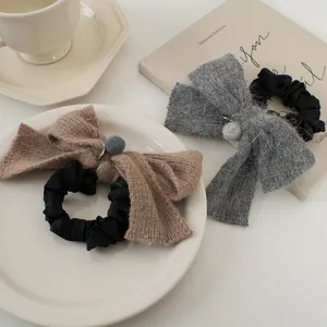 Détail de chouchous nœuds tricotés avec breloques en peluche dans les tons gris et café