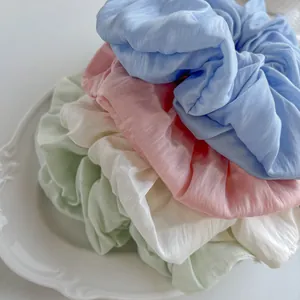 Macro shot of oversized fabric scrunchies in pastel colors on a vintage ceramic plate