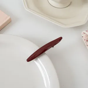 Gros plan d'une barrette rouge foncé brillante sur un plateau en céramique