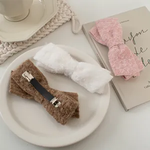 Detailansicht von drei Woll-Haarspangen in Kaffee, Weiß und Rosa mit flauschiger Textur