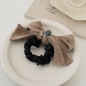 Détail du chouchou nœud tricoté marron café avec breloque smiley sur assiette blanche