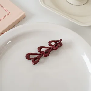 Détail d'une pince à cheveux vintage rouge foncé brillante avec motifs en métal