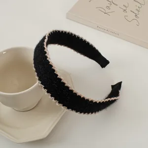 Détail d'un serre-tête en peluche noire avec des bords matelassés ondulés beige en tissu