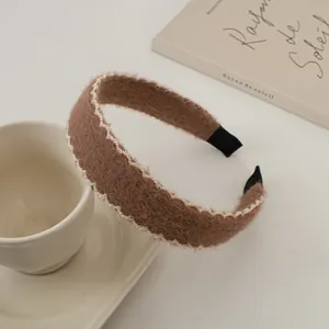 Gros plan d'un serre-tête en peluche marron avec dentelle blanche sur une tasse à café