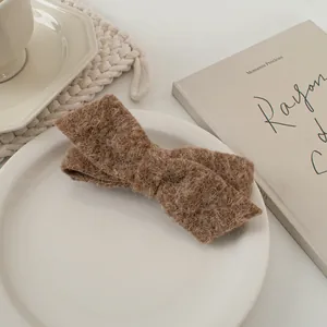 Nahaufnahme brauner Woll-Bogenspange auf Keramikteller in elegantem Ambiente