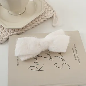 Detailansicht einer weichen weißen Plüsch-Schleifenspange auf einem Buch im Scandi-Stil