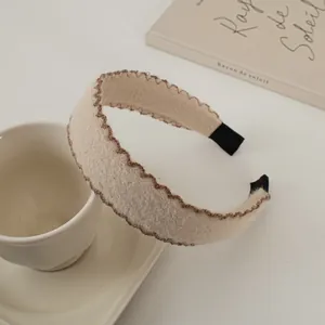 Détail du serre-tête en laine beige avec bordure tricotée marron et doublure textile