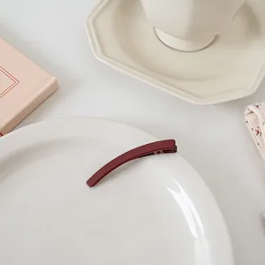 Détail de la barrette rouge foncé mat avec dents antidérapantes sur une assiette blanche