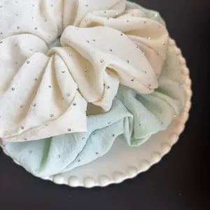 Coleteros grandes de tela con cristales brillantes en blanco y verde menta en plato