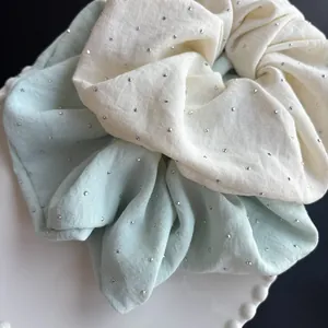 Detalle de coleteros XL verde menta y crema con brillantes plateados en la tela