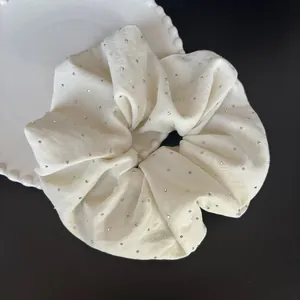 Detalle de coletero crema con diamantes de imitación en un plato decorativo blanco