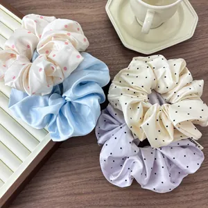 Detailed view of four colorful satin polka dot scrunchies on a wooden table setup