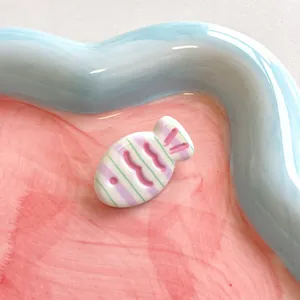 Close-up of cute fish-shaped ceramic hair clip with pink stripes and glossy finish