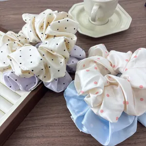 Polished satin polka dot scrunchies in cream and blue displayed on a wooden table