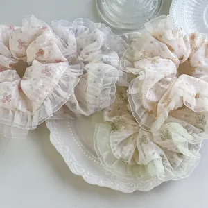 Florale Haargummis aus Organza mit Schleifenmuster und gerüschten Kanten in Cremeweiß