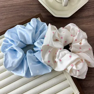 Detail view of colorful satin polka dot oversized scrunchies on a wooden tray