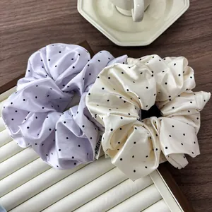 Close-up of lilac and beige polka dot satin scrunchies displayed on a jewelry tray