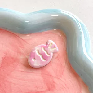 Close-up of cute fish-shaped hair clip with pink and white checkered ceramic texture