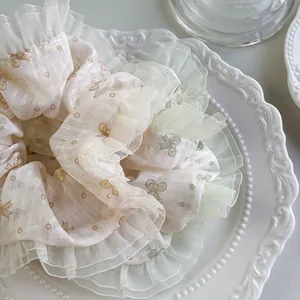 Detailansicht von hellgrünem Organza-Haargummi mit Blumen- und Schleifenmusterung