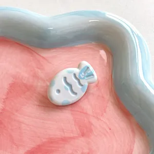 Macro view of a cute blue and white ceramic fish hair clip with polka dot texture