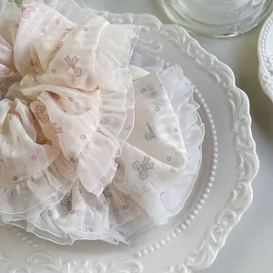 Nahaufnahme eines geschichteten Haargummis aus Netzstoff mit rosa Schleifenmustern