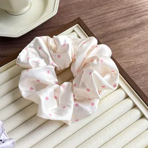 Close-up of pink polka dot satin scrunchie on a decorative jewelry tray for hair styling