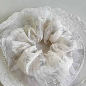Detail von floralem Organza-Haargummi mit blauen Schleifen und doppeltem Spitzenrand